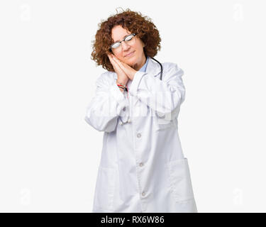 Mitte ager leitender Arzt Frau über isolierte Hintergrund müde schlafen, träumen und mit den Händen posiert zusammen, während lächelnd mit geschlossenen Augen. Stockfoto