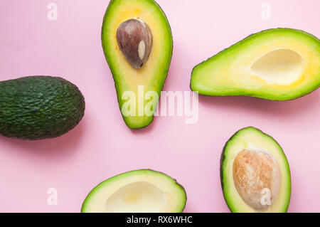 Organische Avocados mit Samen reif, Avocado-, halbe und ganze Früchte auf rosa Hintergrund. Stockfoto