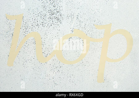 Eine Nahaufnahme des Wortes Hop in hellem Gelb auf einem Whited Out Shop Fenster Stockfoto