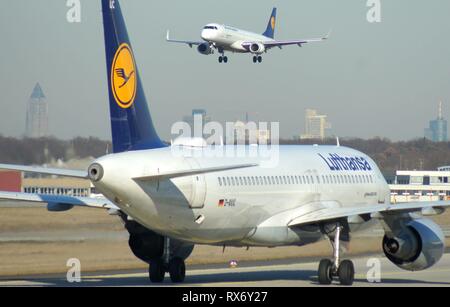 Rhein-Main-Flughafen Frankfurt. Start- und Landebahn Nordwest. Nach der Landung, ein Airbus A320-200 der Lufthansa, Brötchen an die Klemmen auf den wichtigsten Teil des Flughafens, während eine Embraer ERJ190 der Lufthansa derzeit nähert sich. | Verwendung weltweit Stockfoto