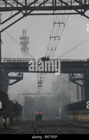Blick auf Werk Slums mit Metallgehäuse und Maschinen für die Produktion der Kokerei Industrie, offenem Feuer und Rauch Bildschirm in einem Werk in der Ukraine Stockfoto