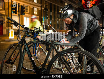 Radfahrer, die roten Rosen Entriegelung bike wie Abbildung der Radfahrer führt hinter nachts Spitalfield East London unscharfe, Großbritannien Stockfoto