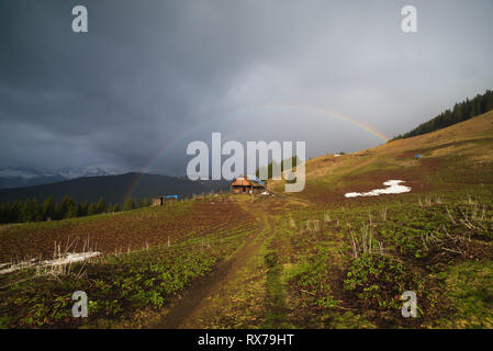 Landschaft im Bergdorf. Regenbogen über dem Haus Stockfoto