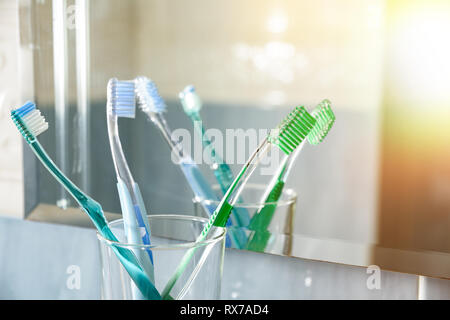 Zahnbürsten in einem Glas Vase in einem blauen Badezimmer vor dem Spiegel. Horizontale Komposition. Vorderansicht. Stockfoto
