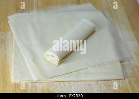 Spring Roll Wrapper auf Holztisch. Frühlingsrollen-Wrapper werden aus Weizenmehl und Wasser hergestellt, werden im Allgemeinen gefroren verkauft und sind sehr dünn ähnlich. Stockfoto