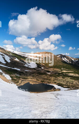 See in den Bergen. Frühling Landschaft mit blauem Himmel und Cumuluswolken. Sonnigen Tag. Der letzte Schnee auf den Pisten. Karpaten, Ukraine, Europa Stockfoto