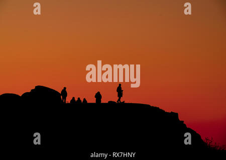 Silhouette von Menschen auf einem Berg bei Sonnenuntergang mit roten Himmel Stockfoto