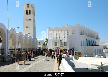 SANTORINI, Griechenland - 19 JULI 2018: Touristen wandern in Santorini, in der Nähe der orthodoxen Kirche mit Hotel Atlantis auf dem Hintergrund, das Dorf Oia, Griechenland Stockfoto