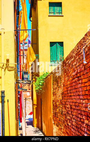 Schmale Seitenstraße zwischen alten gelben Häuser in Burano, Venedig, Italien Stockfoto