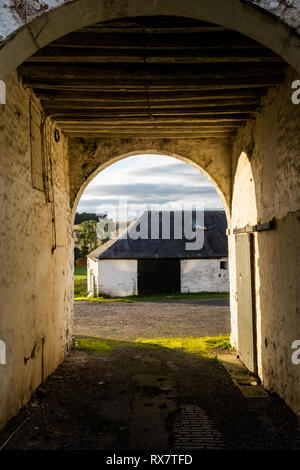 Auf der Suche durch die gewölbten Öffnung eines alten Rinder Hof und landwirtschaftlichen Gebäuden. Enterkine farm Ayrshire, Schottland Großbritannien Stockfoto