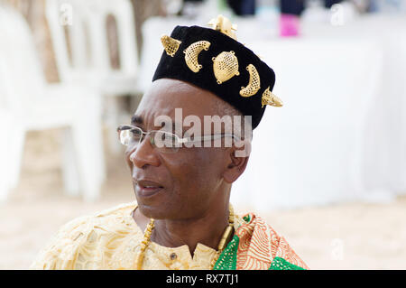 Bassam, Côte d'Ivoire - 7 November 2015: Portrait eines älteren Bürgers in einem goldenen Hut sitzt und wartet auf den Beginn des Festivals Stockfoto