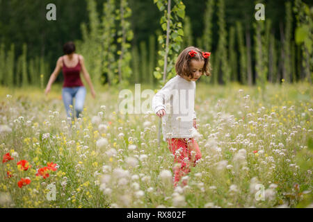 Mutter mit ihrer kleinen Tochter in Mohnfeld Stockfoto