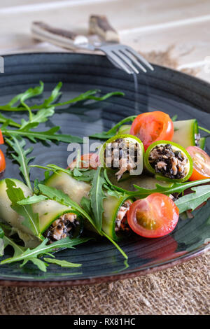 Gehackte Räucherlachs und schwarzen Oliven, Gurke, dekoriert mit Tomaten und Rucola gerollt Stockfoto