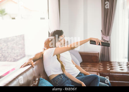 Paar auf dem Sofa mit der Fernbedienung vor dem Fernseher im Wohnzimmer Stockfoto