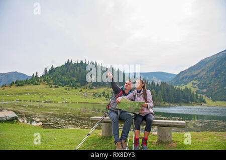 Wandern Paar. Junges Paar mit Rucksäcken auf der Karte suchen am See Stockfoto