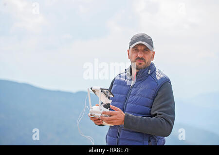 Männliches Modell verwenden, Bärtigen drone Fernbedienung auf das Gerät in der Luft zu fliegen. Mann die Drohne in der Natur fliegen. Neue Technologien und Innovationen Konzept. Stockfoto