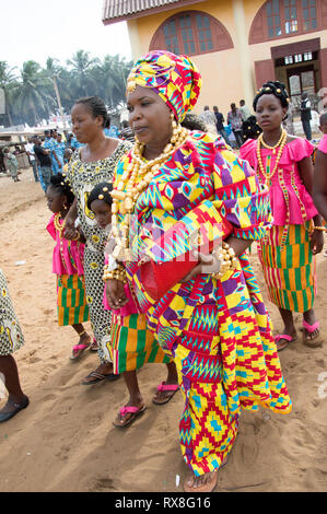 Bassam, Côte d'Ivoire - November 7, 2015: Die Queen in der traditionellen loincloths, Armband, Ohrringe und Halsketten Gold gekleidet ist durch wenig begleitet Stockfoto