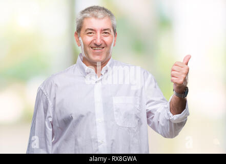 Gut aussehender älterer Mann über isolierte Hintergrund lächelnd mit glücklichen Gesicht und zeigt auf die Seite mit dem Daumen nach oben. Stockfoto