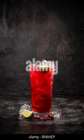 Erfrischung alkoholische rote Cranberry und lime Cocktail mit Eis auf dunklem Hintergrund, kopieren Raum Stockfoto