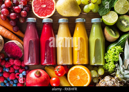 Bunte Smoothies in Flaschen und frische Obst und Gemüse auf Holztisch, Ansicht von oben. Stockfoto