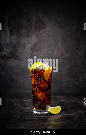 Glas cuba libre mit Kalk auf schwarzem Hintergrund Stockfoto