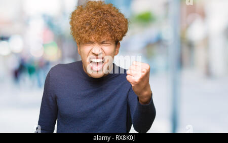 Junger stattlicher Mann mit afro Haar verärgert und wütend die Faust frustriert und wütend, während Schreien vor Wut. Wut und aggressives Konzept. Stockfoto