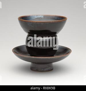 Cup und Cupstand. China. Datum: 1000-1099. Maße: Gesamt: h. 10,3 cm (4 1/16 in.); Durchm. 11,3 cm (4 7/16 in.); Schale: h. 4,4 cm (1 3/4 in.); Durchm. 9,5 cm (3 3/4 in.); Stand: h. 6,9 cm (2 3/4 in.); Durchm. 11,3 cm (4 7/16 in.). Northern schwarz Ware, cizhou Typ; hellgrau Steinzeug mit dunklen braunen Glasur. Herkunft: China. Museum: Das Chicago Art Institute. Stockfoto