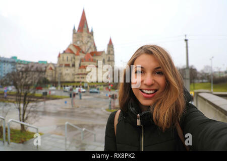 Touristische Mädchens selfie in Wien mit St. Franziskus Kirche auf dem Hintergrund Stockfoto