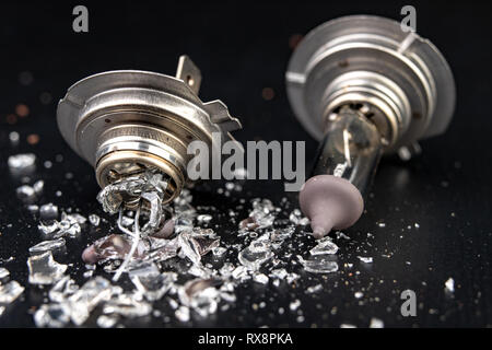 Kaputte Glühbirne für das Auto Scheinwerfer. Verschüttete Glas und defekten Heizdraht auf der Workshop Tabelle. Der dunkle Hintergrund. Stockfoto