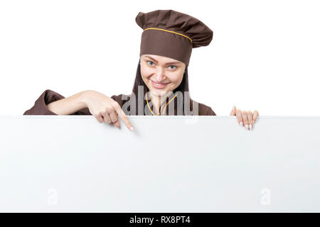 Schöne Köchin Zeigefinger nach unten zeigt auf grau Blank Board mit Kopie Speicherplatz auf weißem Hintergrund Stockfoto