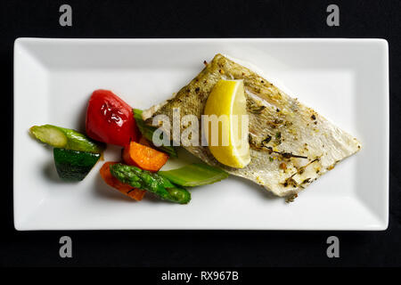 Gegrilltes Zanderfilet mit gemischten gegrilltes Gemüse auf weißen rechteckigen Platte von oben. Schwarzen Hintergrund. Stockfoto