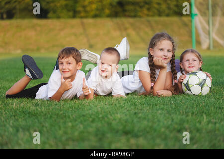 Glückliche Kinder liegen auf dem Fußballplatz Stockfoto