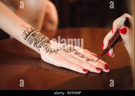 Master mehndi Henna zieht auf Eine weibliche Hand. Stockfoto