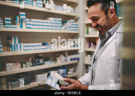 Reifen Apotheker mit einem Rezept auf der Suche nach richtige Medikament in der Apotheke. Apotheker, die Verschreibung und Kontrolle der Arzneimittel in der Apotheke. Stockfoto