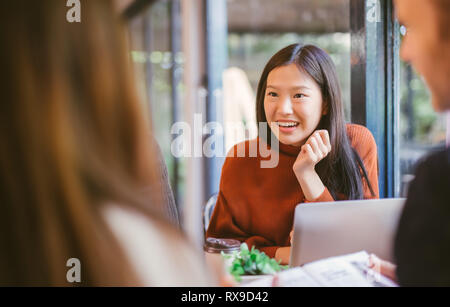 Junge asiatische Mädchen eine Freunden plaudern und mit Laptop im Café im Café Café an der Universität sprechen und gemeinsam lachen. Stockfoto