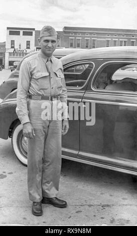 Vertikale shot der jungen amerikanischen Soldaten in Uniform neben einem Auto gerade vor dem Europäischen Bereitstellung. Eingescannten alten Familienfoto. Mai contai Stockfoto