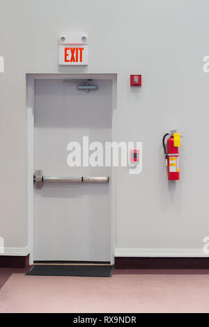 Vertikaler ein Notausgang Tür mit einem Feueralarm, Feuerlöscher, und Notfall Licht an der Wand hängen. Stockfoto