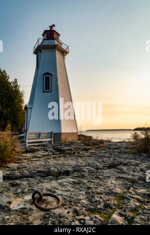 Sonnenaufgang und dem historischen Leuchtturm am grossen Whirlpool Hafen. Dock ring in Rock wurde verwendet, um Schiffe Zuflucht nehmen Stürme zu binden. Tobermory, Ontario, Kanada Stockfoto