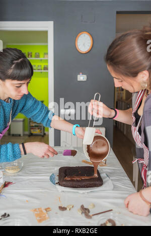Mutter mit Tochter Schokolade Kuchen auf den Tisch zu Hause. Stockfoto