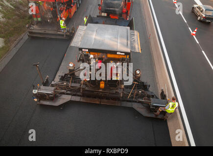 Asphalt Anwendung auf einer Schnellstraße. Zwei Fertigern in Aktion. nach oben Blick auf den Bohlen. Stockfoto