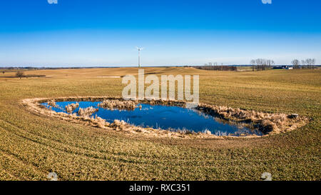 Luftaufnahme der Windenergieanlage auf dem Feld und einem kleinen Teich Stockfoto