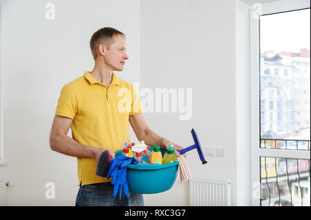 Der Mann hält ein Becken mit Reinigungsmittel für zu Hause gefüllt. Stockfoto