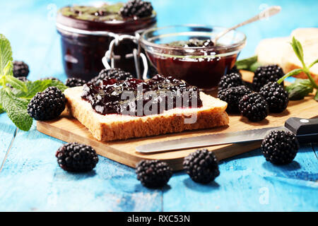 Toastbrot mit hausgemachten blackberry Jam oder Marmelade auf rustikalen blau Tisch serviert mit Butter zum Frühstück oder Brunch Stockfoto