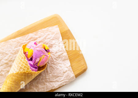 Multi-pink, blau und violett Eis Ball mit Kaugummi Geschmack in eine Waffel Kegel auf eine Holzplatte Stockfoto