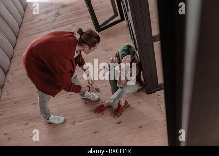 Frau sitzt auf dem Boden und aggressiven Mann an ihrer schreienden Stockfoto