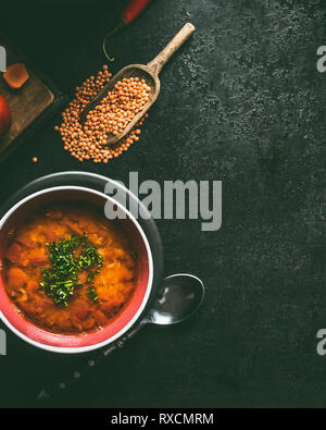 Rote Linsensuppe in der Schüssel auf dunklen rustikalen Hintergrund, Ansicht von oben mit der Kopie. Vegane und vegetarische Kost Stockfoto