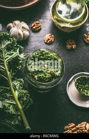 Frischen Grünkohl pesto in Glas mit kale Blatt auf dunklen Küche Tisch Hintergrund, Ansicht von oben Stockfoto