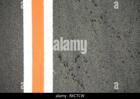 Die drei senkrechten weißen und orangefarbenen Linien auf grauem Asphalt mit Platz für Texte auf der rechten Seite (Kopie) Stockfoto