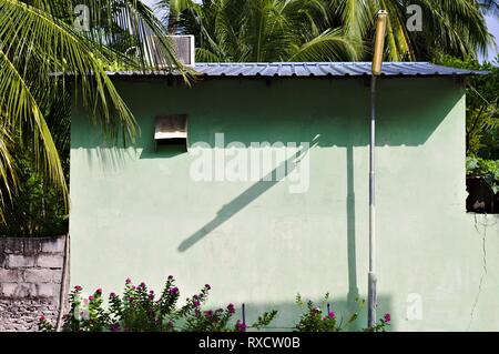 Straßenlaterne Schatten auf einem verlassenen Haus mit violetten Blumen und Palmen Blätter (Ari Atoll, Malediven) Stockfoto