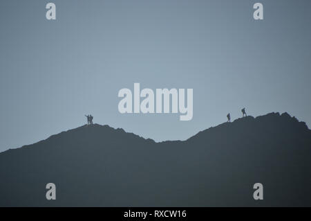 Silhouetten der Wanderer eine Selfie auf Schreitenden Kante auf dem Weg zum Wainwright Helvellyn im Nationalpark Lake District, Cumbria, England, UK. Stockfoto